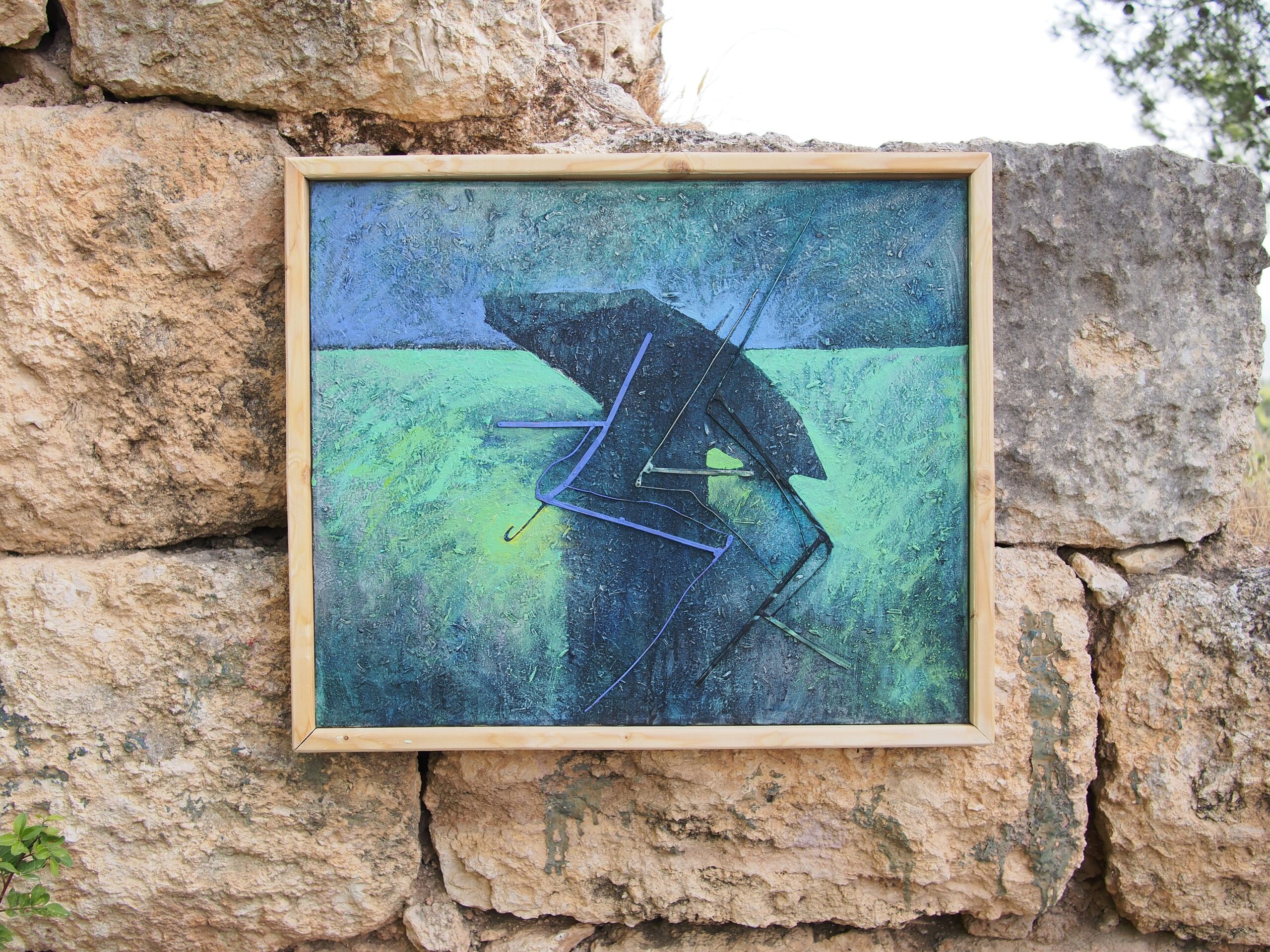 Painting showing the umbrella canvas, framed in pale wood and hung on a rough dry-stone wall outdoors - the work returned to the open air and the elements it once sheltered against.